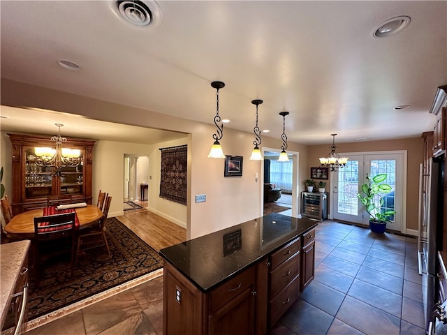 kitchen featuring dark brown cabinets, a center island, an inviting chandelier, and hanging light fixtures