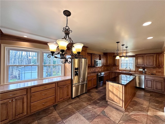 kitchen featuring decorative backsplash, a wealth of natural light, a kitchen island, and stainless steel appliances