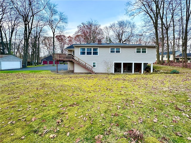 rear view of property with a garage, an outdoor structure, a yard, and a wooden deck