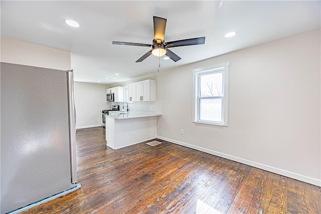 kitchen featuring dark wood-type flooring, white cabinets, sink, kitchen peninsula, and stainless steel appliances