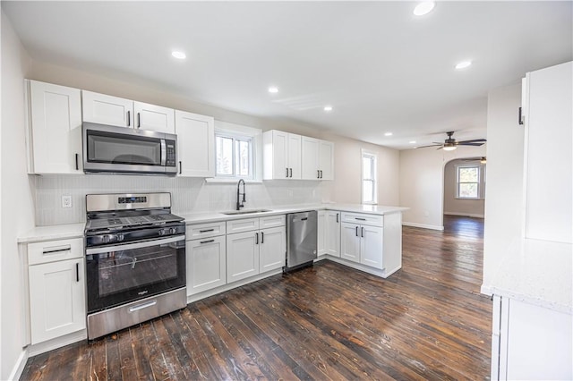 kitchen featuring a wealth of natural light, sink, dark wood-type flooring, white cabinets, and appliances with stainless steel finishes