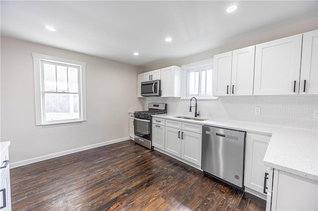 kitchen featuring appliances with stainless steel finishes, dark hardwood / wood-style flooring, white cabinetry, and sink