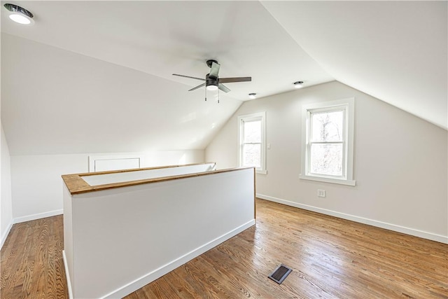 bonus room with light wood-type flooring, vaulted ceiling, and ceiling fan