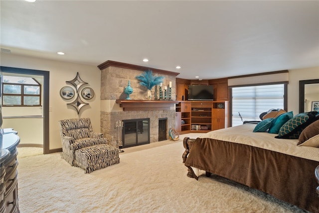 bedroom with multiple windows, a fireplace, and light colored carpet