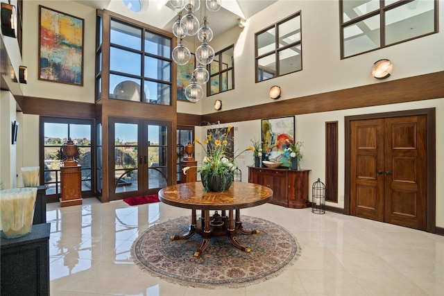 entrance foyer featuring french doors, a towering ceiling, and a chandelier