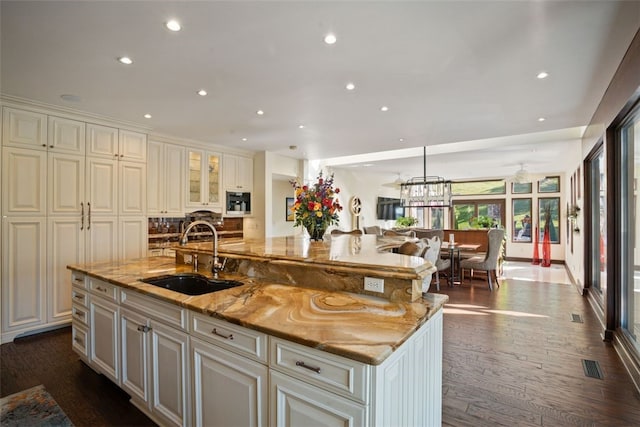 kitchen with dark hardwood / wood-style flooring, a large island, sink, and light stone counters