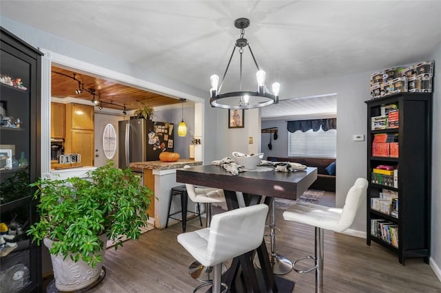 dining space featuring dark hardwood / wood-style flooring, wood ceiling, and an inviting chandelier