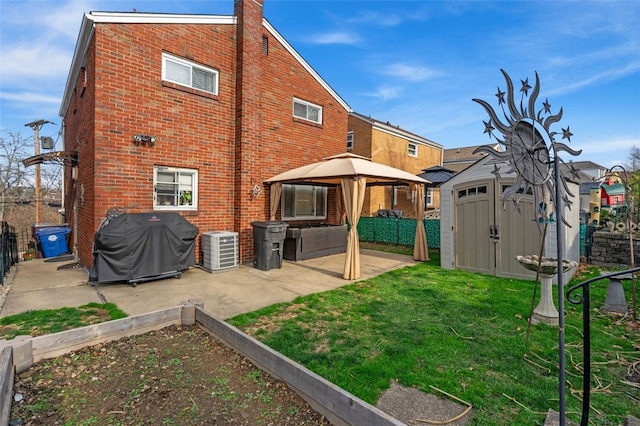 back of property with a gazebo, central AC unit, a patio area, a yard, and a storage unit