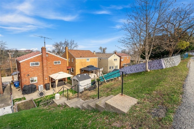 back of house with a lawn and a storage unit