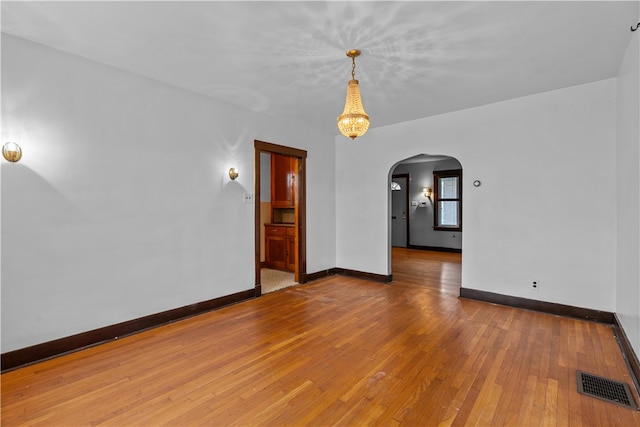 spare room featuring hardwood / wood-style flooring and a notable chandelier