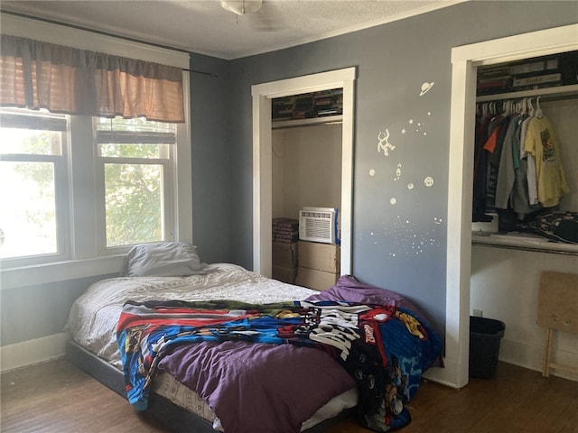 bedroom featuring wood-type flooring, a textured ceiling, a wall mounted AC, and a closet