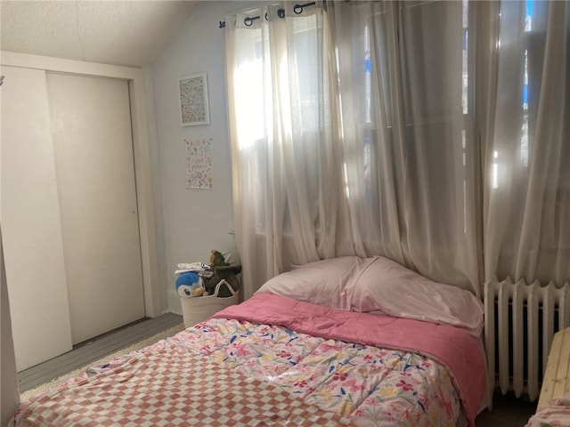 bedroom with a textured ceiling, radiator, and lofted ceiling