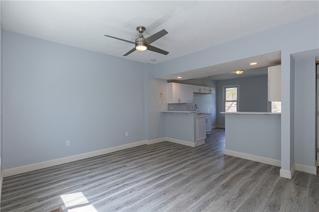 unfurnished living room featuring baseboards, ceiling fan, light wood-type flooring, a sink, and recessed lighting