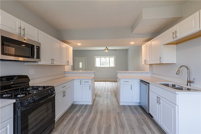 kitchen featuring a peninsula, appliances with stainless steel finishes, light countertops, and white cabinets