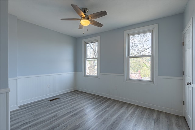 unfurnished room featuring wainscoting, a healthy amount of sunlight, and light wood finished floors