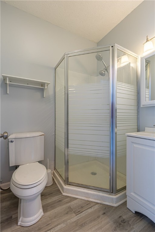 bathroom with a stall shower, a textured ceiling, wood finished floors, and vanity