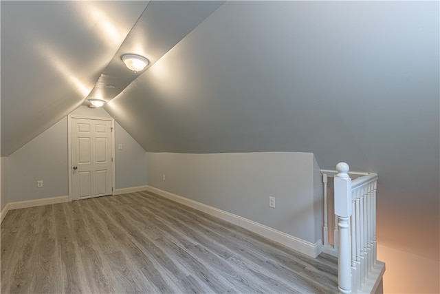 additional living space featuring lofted ceiling, baseboards, and light wood finished floors