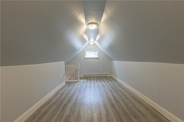 bonus room with light wood-type flooring, a baseboard radiator, lofted ceiling, and baseboards