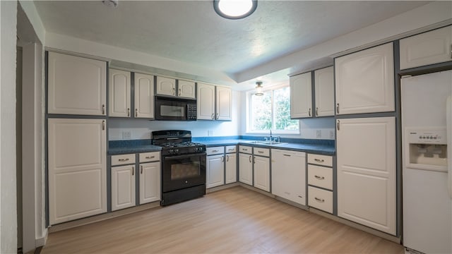 kitchen featuring black appliances, light wood-type flooring, sink, and a textured ceiling