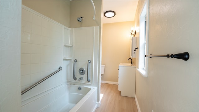 full bathroom featuring toilet, wood-type flooring, vanity, and tiled shower / bath combo