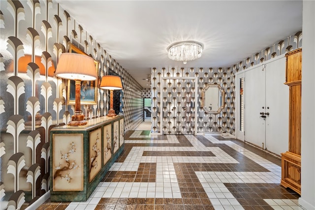 hall with dark tile patterned floors and an inviting chandelier