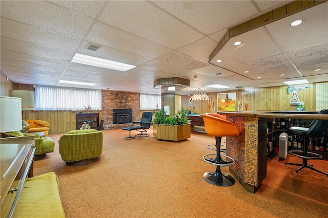 bar featuring carpet floors, a wood stove, a drop ceiling, and wood walls