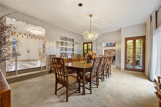 dining area featuring a stone fireplace, light carpet, plenty of natural light, and a notable chandelier