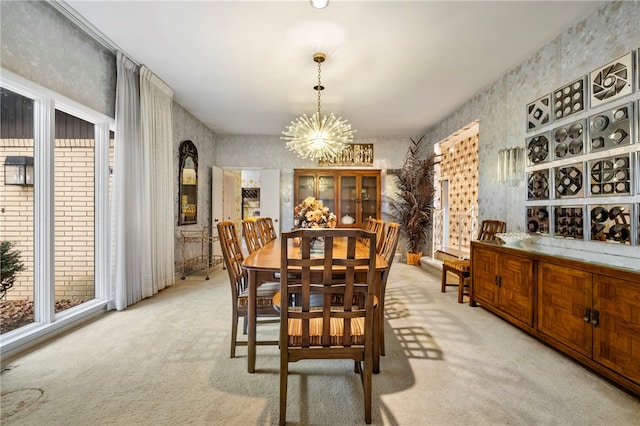 carpeted dining area with a healthy amount of sunlight and an inviting chandelier