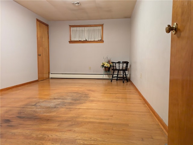 empty room featuring baseboard heating and light wood-type flooring