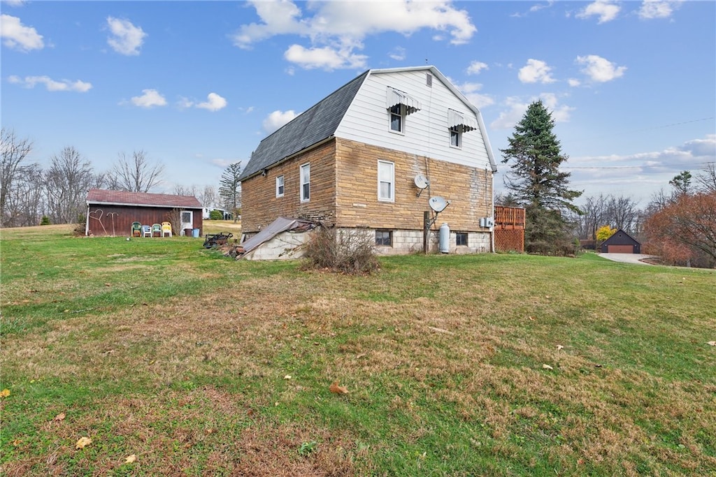 back of house with a lawn and an outdoor structure