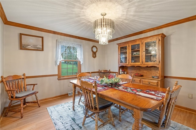 dining space featuring a chandelier, light wood-type flooring, and crown molding