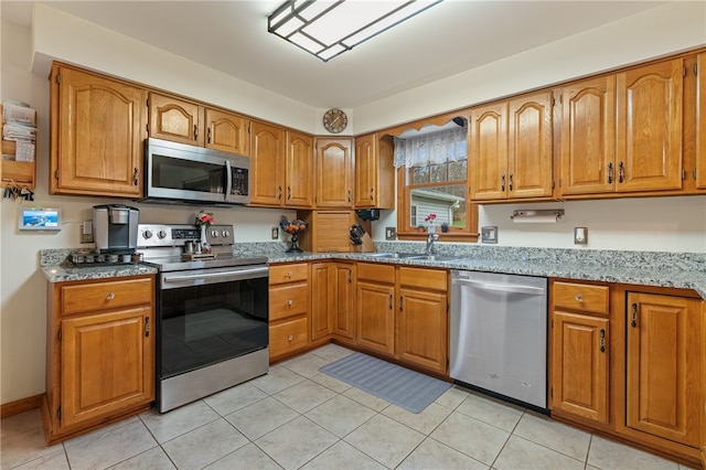 kitchen featuring light stone countertops, sink, light tile patterned flooring, and stainless steel appliances