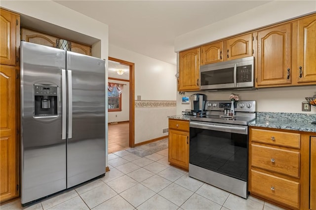 104 Caromar Dr, Adams Twp, PA 16046 - kitchen with stainless steel appliances, brown cabinetry, light tile patterned flooring, and stone counters