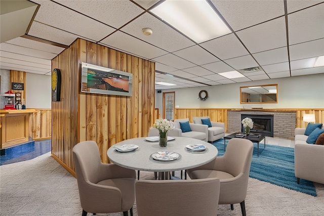 carpeted dining room with a drop ceiling and wood walls