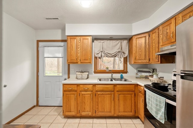 kitchen featuring a wealth of natural light, sink, a textured ceiling, and appliances with stainless steel finishes