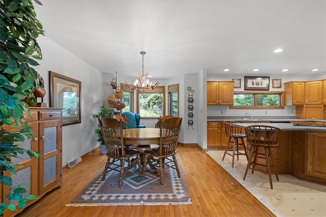 dining area featuring light wood-type flooring, sink, and an inviting chandelier