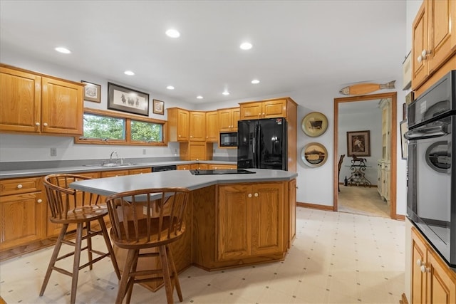 kitchen featuring a breakfast bar, sink, a kitchen island, and black appliances