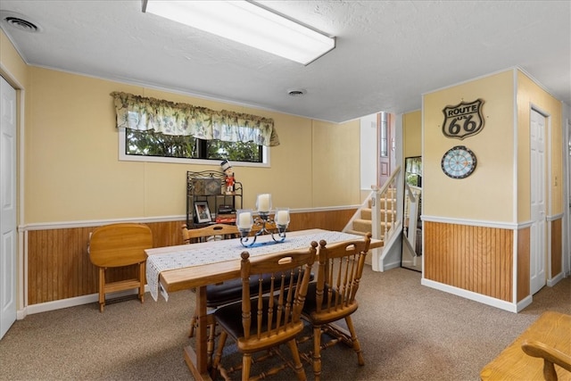 carpeted dining room featuring wood walls and a textured ceiling