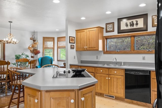 kitchen featuring sink, a kitchen breakfast bar, a chandelier, a kitchen island, and black appliances