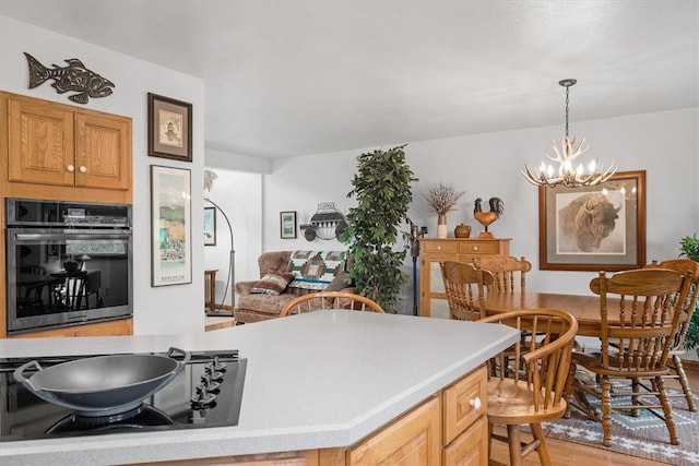 kitchen featuring oven, decorative light fixtures, light hardwood / wood-style flooring, a notable chandelier, and cooktop