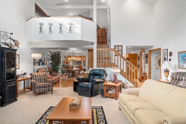 carpeted living room featuring a towering ceiling and a notable chandelier