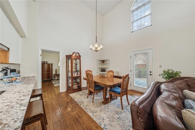 dining room featuring a notable chandelier, wood-type flooring, and high vaulted ceiling