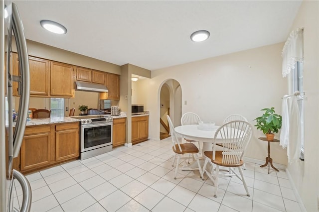 kitchen with light stone countertops, light tile patterned flooring, and appliances with stainless steel finishes