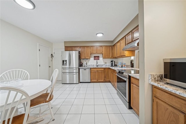 kitchen featuring sink, stainless steel appliances, light stone counters, and light tile patterned flooring