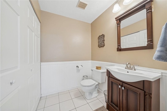 bathroom with toilet, vanity, and tile patterned floors