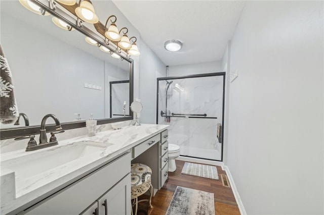 bathroom with hardwood / wood-style floors, vanity, a shower with shower door, and toilet