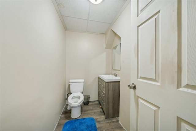 bathroom with hardwood / wood-style floors, vanity, a drop ceiling, and toilet