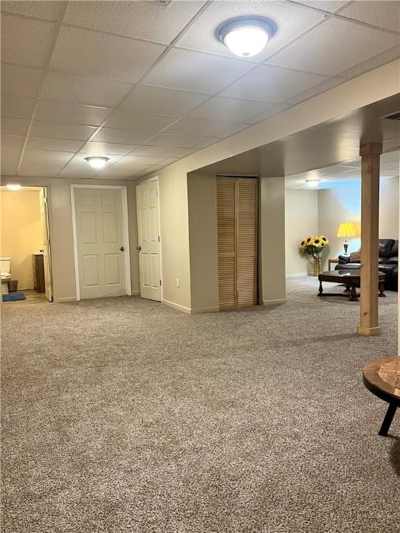 basement featuring a paneled ceiling and carpet