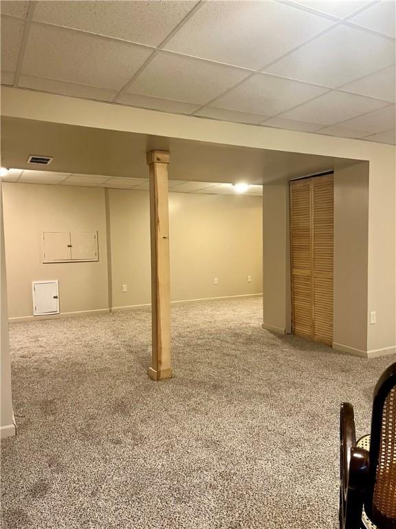 basement featuring a paneled ceiling and carpet floors