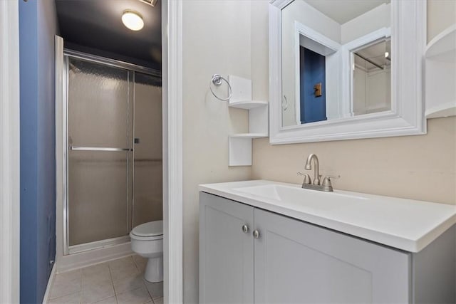 bathroom with tile patterned floors, vanity, toilet, and a shower with door